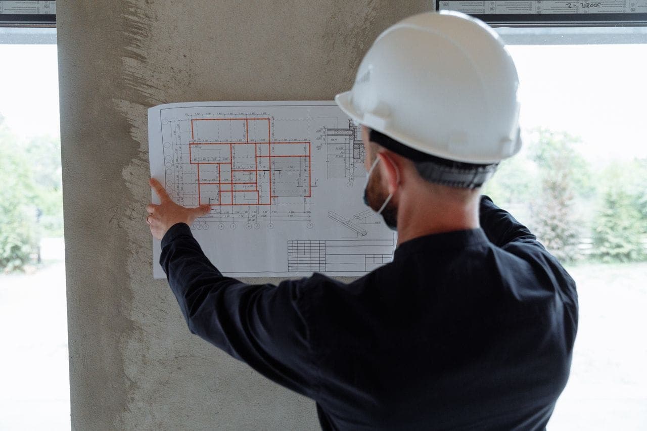 Person i skyddshjälm som studerar en projektritning